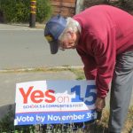 Man setting up 'Yes on 15' sign.